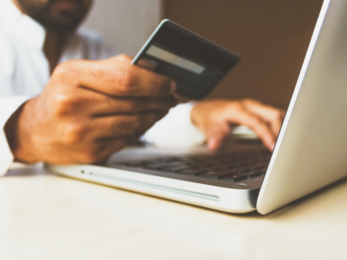 Persona pagando una compra online con tarjeta desde un portátil